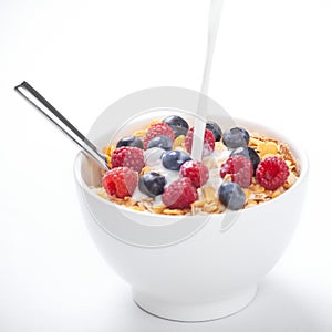 Pouring milk over muesli and fresh fruit, white background