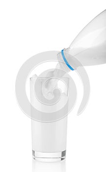 Pouring milk from plastic bottle in glass on white background