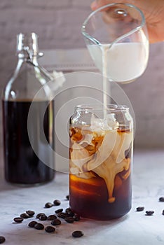 Pouring milk in to a glass of homemade cold brew coffee