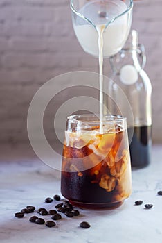 Pouring milk in to a glass of homemade cold brew coffee
