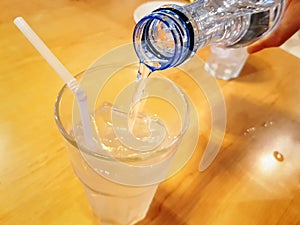 Pouring Mineral Drinking Water From Bottle Into Glass with Ice Cubes