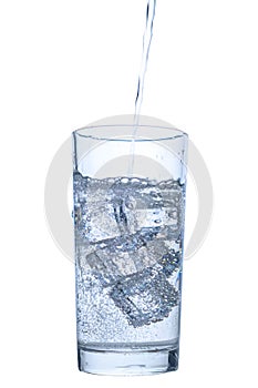 Pouring mineral water in transparent glass with ice and bubbles isolated over white background, close up