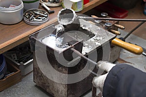 Pouring molten lead alloy into a mold. Workshop.