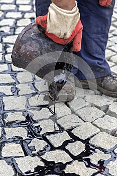 Pouring molten pitch from a tar bucket