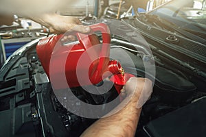 Pouring new engine oil from canister into motor funnel at car service, close up