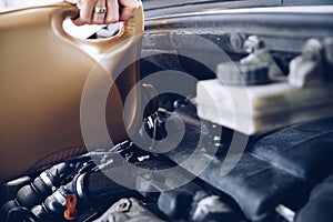 Pouring oil into the car engine. Close up of a woman's hand.