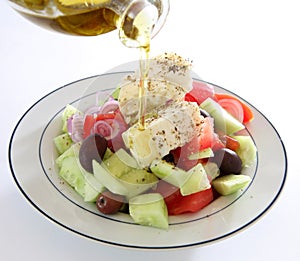 Pouring oil on Greek salad