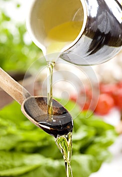 Pouring oil in the salad over a wooden spoon