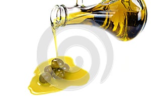 Pouring olive oil from a bottle into a green olives