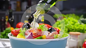 Pouring Olive oil on fresh Vegetable salad, Greek salad on white table