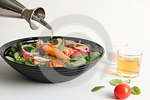 Pouring olive oil to salmon salad bowl