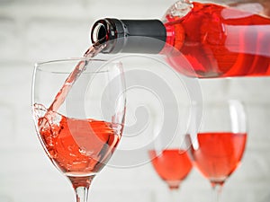 Pouring pink wine from bottle into wineglass