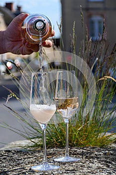 Pouring of premier cru sparkling rose wine with bubbles champagne with view on old houses of Hautvillers, where lived Benedictine photo