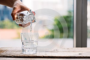 Pouring purified fresh drink water from the bottle on table in l photo