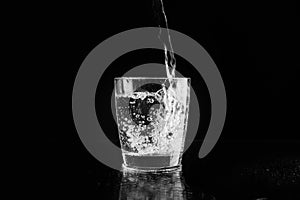 Pouring purified fresh water in glass on background