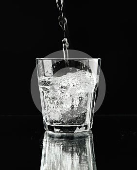 Pouring purified water in glass on mirror background