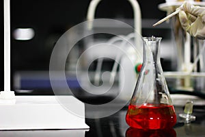 Pouring a red chemical on a glass conical flask with a dropper in a chemistry lab