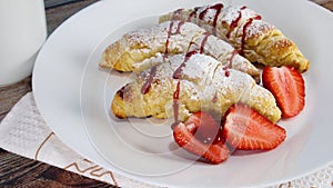 Pouring red syrup on sweet croissants on white plate. Delicious croissants for breakfast or snack