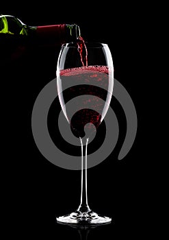 Pouring red wine from bottle to glass on black