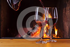 Pouring red wine at cozy fireplace