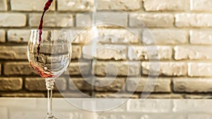 Pouring red wine into a glass against a white brick wall background,warm shades,close-up