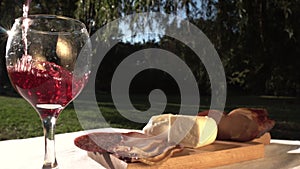 Pouring Red Wine in Glass at Outdoor Picnic Table on a Sunny Day With Refection