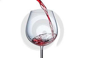 Pouring red wine into a glass with splashes on a white background