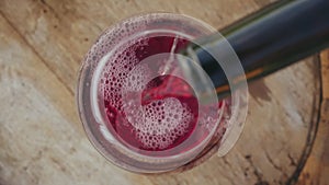 Pouring red wine into a glass, top view