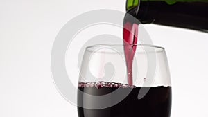 Pouring red wine into a glass. Top view of wineglass full of alcohol drink on white background