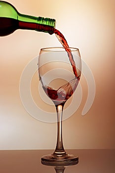 Pouring red wine into the wineglass close-up, isolated on pink gradient background