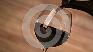 Pouring red wine and wooden background