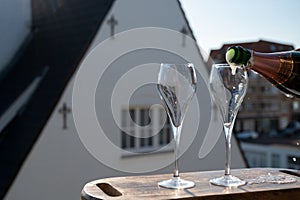 Pouring of rose champagne sparkling wine in flute glasses on outdoor terrace in France