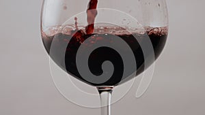 Pouring rose wine glass goblet in super slow motion close up. Red merlot flowing