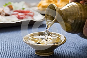 Pouring sake into a small Japanese cup