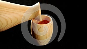 Pouring sake from wooden hinoki sake bottle, tokkuri, into wooden cup, Guinomi or Ochoko.