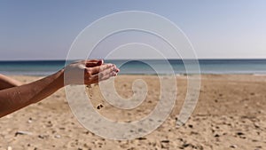 Pouring sand in woman`s hand. Sand is falling through her fingers.Woman pours beach sand from her hands.