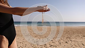 Pouring sand in woman`s hand. Sand is falling through her fingers.Woman pours beach sand from her hands.