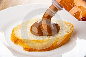 Pouring slice of bread boiled condensed milk from plastic pack  in plate