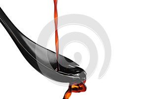 Pouring soy sauce into spoon against white background