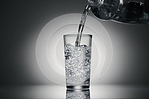 Pouring sparkling water in a glass on a dark background