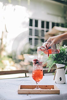 Pouring strawberry, berry and black berry fruit juice drink into glass