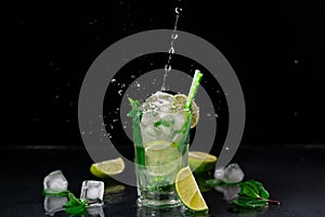 A Pouring Stream of Water into a glass of Mojito against a black background