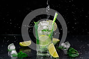 A Pouring Stream of Water into a glass of Mojito against a black background