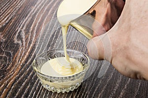 Pouring sweet condensed milk from metallic jar in bowl