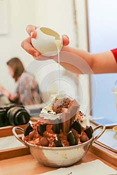 Pouring sweetened condensed milk on top of chocolate bingsu.