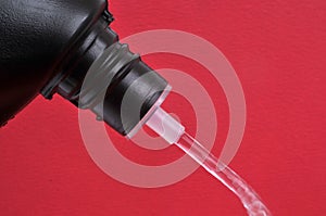 Pouring toilet product close-up on red background