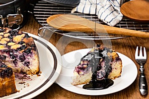 Pouring topping chocolate on a piece of delicious homemade blueberry and crumble cheesecake