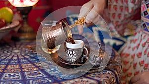 Pouring turkish coffee from cezve into cup