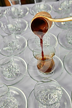 Pouring turkish coffee into traditional embossed cup.