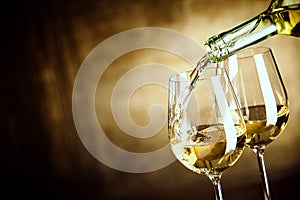 Pouring two glasses of white wine from a bottle photo